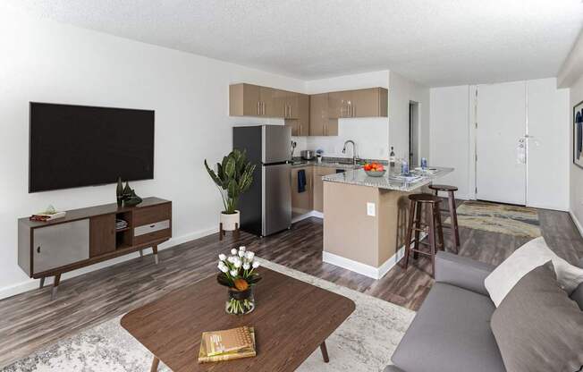 A modern living room with a flat screen TV, a wooden coffee table, and a grey sofa.