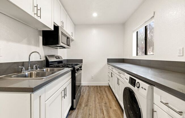A modern kitchen with white cabinets and stainless steel appliances.