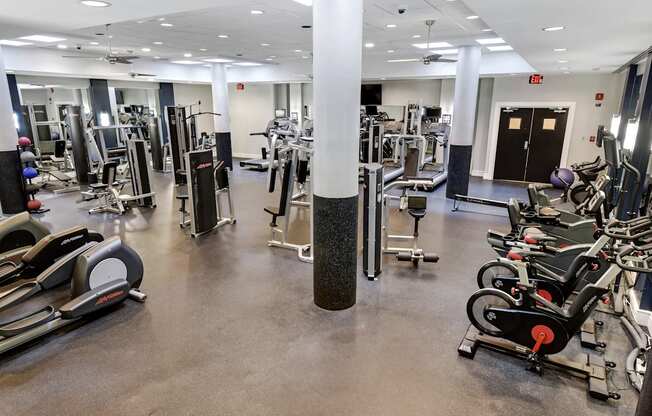 A gym with a variety of equipment including treadmills, weights, and exercise machines.