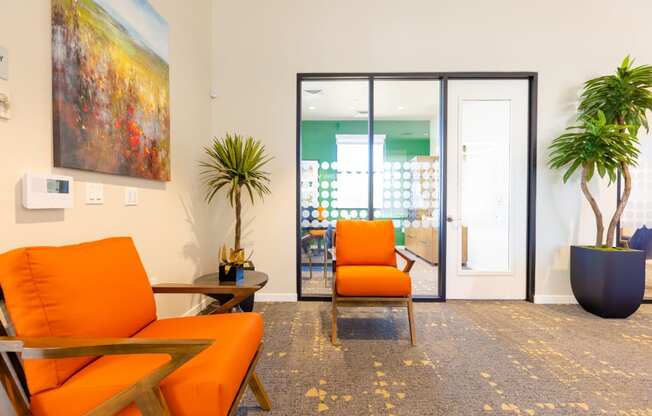 a living room with orange chairs and a sliding glass door