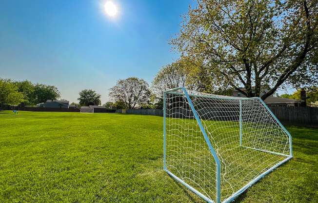 a soccer goal on a grassy field with trees in the background  at Park On Canal Apartments, Clinton Twp