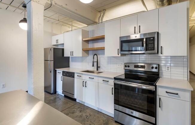 a kitchen with white cabinets and stainless steel appliances at Highland Mill Lofts, Charlotte