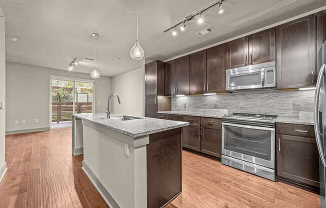A modern kitchen with dark brown cabinets and a wooden floor.