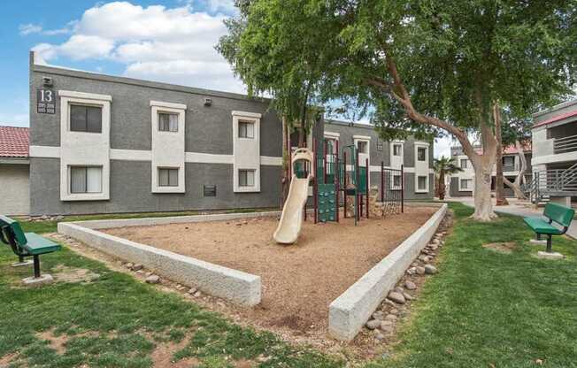 A playground area in front of a grey building with the number 13 on it.