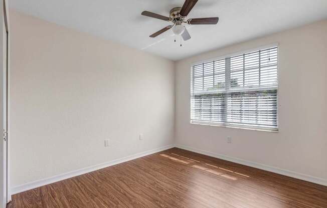 A room with a ceiling fan and a window with blinds.