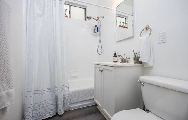 a bathroom with white walls and a white toilet next to a white vanity with a white sink