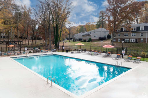 a pool with chairs and umbrellas next to a building