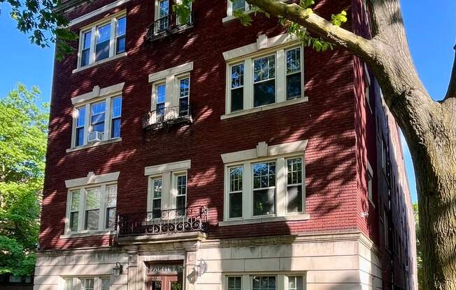 A red brick building with a tree in front.