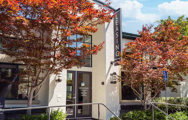 A leasing office building with trees in front.