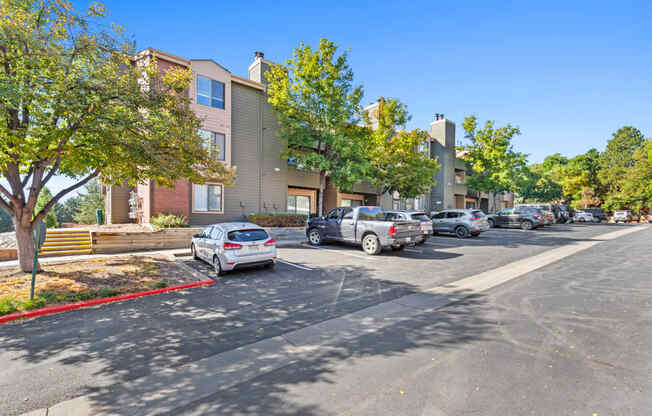 a parking lot with cars parked in front of apartment buildings