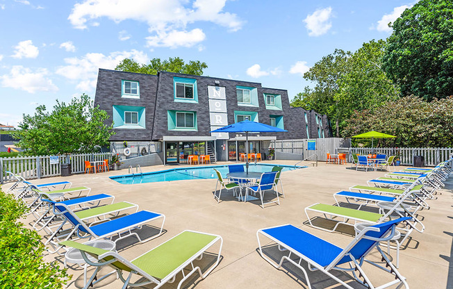 a pool with chairs and umbrellas in front of a building