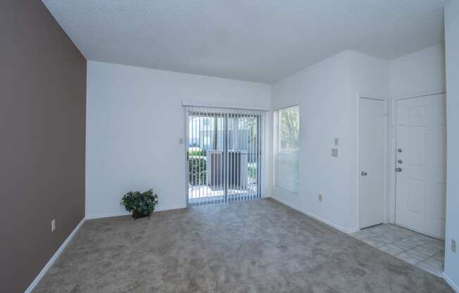 an empty living room with a door leading to a balcony