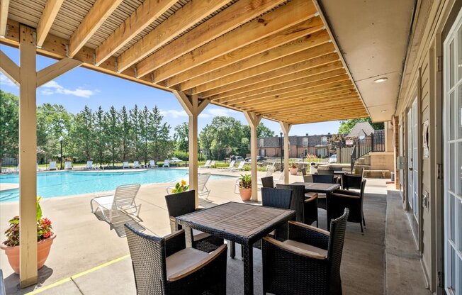 A patio with a table and chairs overlooking a pool.