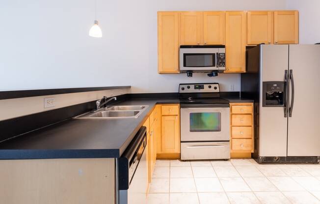 a kitchen with black countertops and wooden cabinets at 26 West, Managed by Buckingham Urban Living, Indianapolis