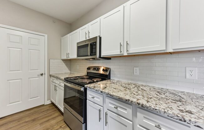 A kitchen with white cabinets and a granite countertop.