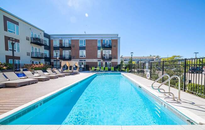 A large swimming pool in front of a multi-story apartment building.