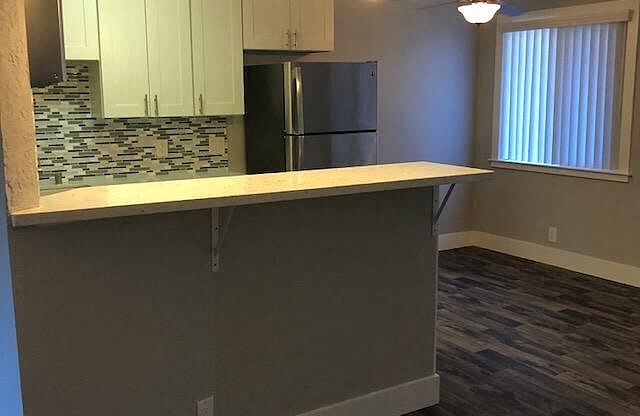 A kitchen with a refrigerator, cabinets, and a countertop.