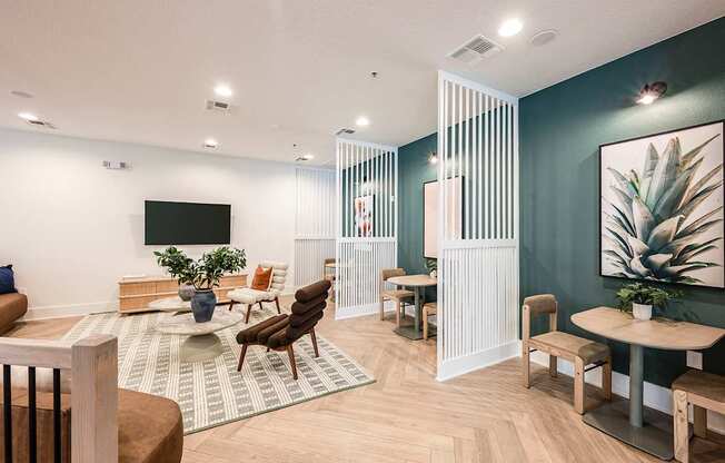 A modern living room with a white sofa, wooden chairs, and a TV on the wall.