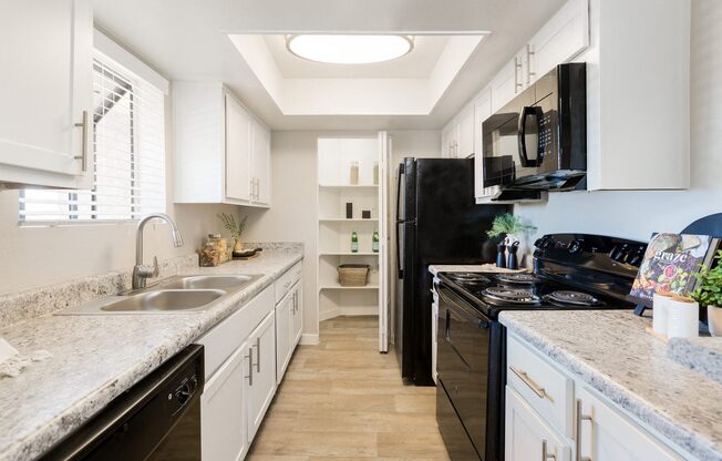 a kitchen with white cabinets and black appliances