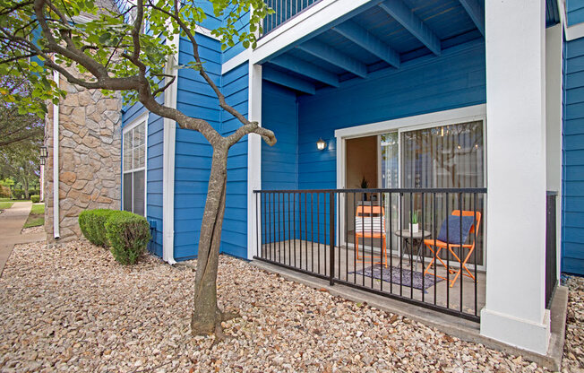 a blue house with a balcony and a tree
