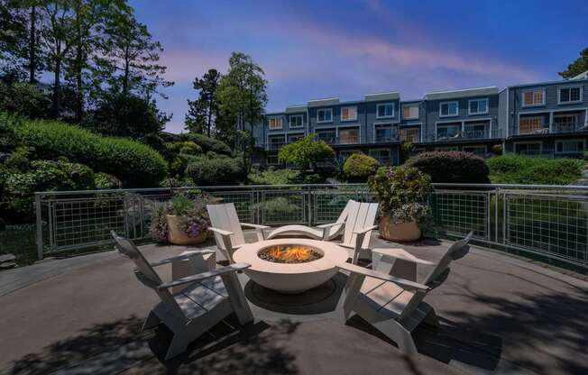 A fire pit sits in the middle of a patio surrounded by four chairs.