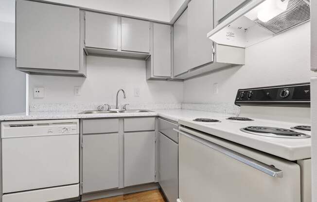 A white kitchen with a stove top oven and a dishwasher.