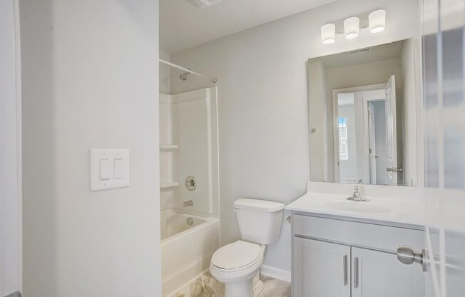 A white bathroom with a toilet, sink, and bathtub.