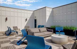 a patio with a couch chairs and coffee table in front of a white building