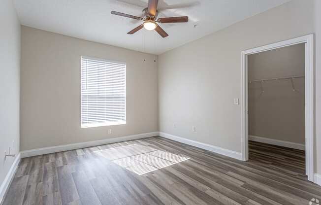 an empty living room with a ceiling fan and a closet