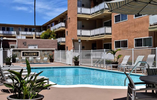 View of gated community pool with lounge chairs and seating with umbrellas