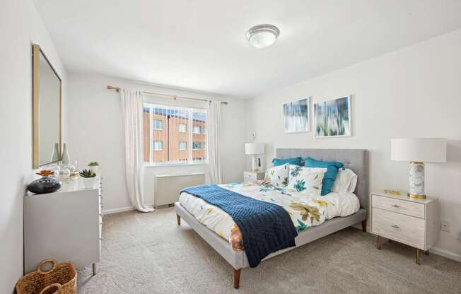 A bedroom with a bed, nightstand, and window.