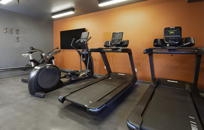 a gym with three treadmills and a tv