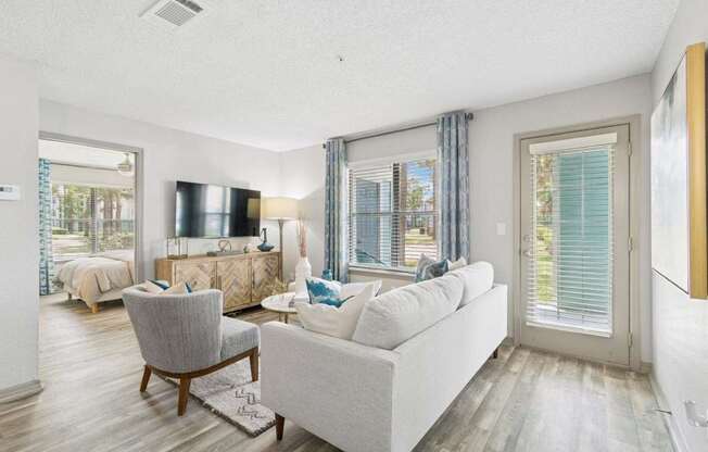 A living room with a grey couch, a chair, and a television.