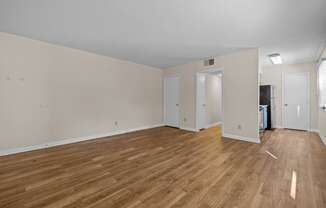 the living room and dining room of an apartment with wood flooring