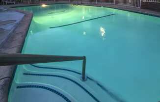 a large pool with a fence around it and a light shining on the water