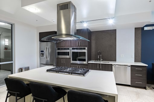 a kitchen with a large island with a stove and a refrigerator