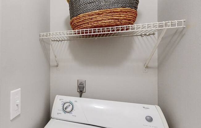 a washer and dryer in a laundry room with a basket on the wall