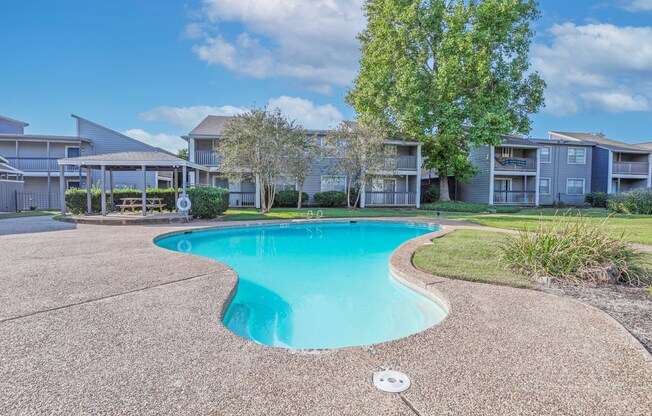 Our sparkling swimming pool with apartment buildings in the background at Laurel Parc apartments in Shreveport, LA.