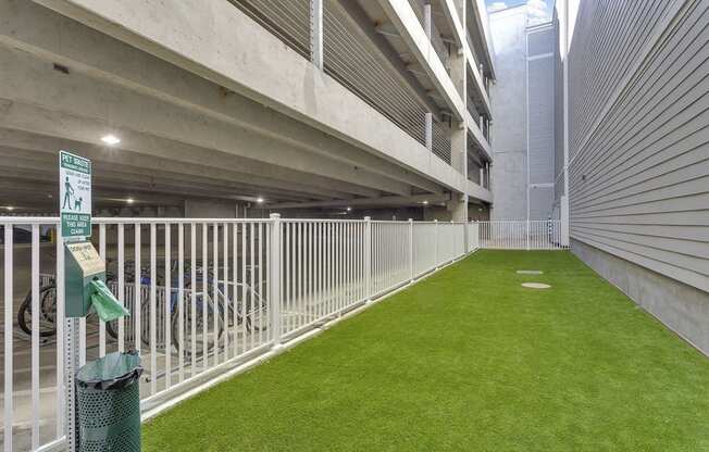 A parking garage with a green sign and a green trash can.