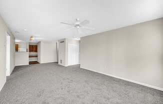 an empty living room with carpet and a ceiling fan
