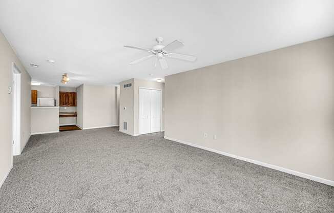 an empty living room with carpet and a ceiling fan