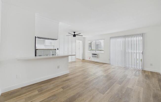 A spacious room with wooden flooring and white walls.