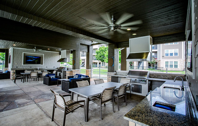 a covered patio with a kitchen and dining area