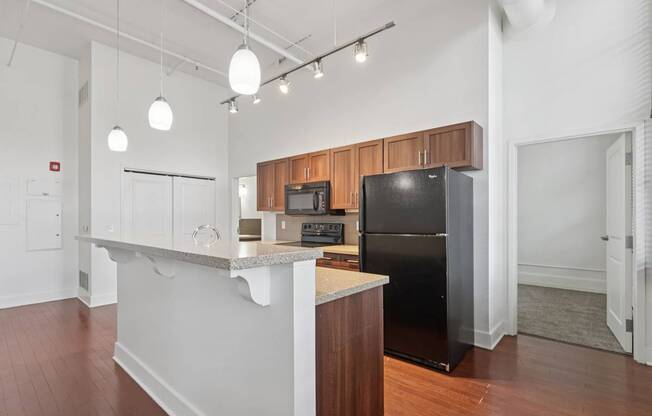 A kitchen with a black refrigerator and wooden cabinets.