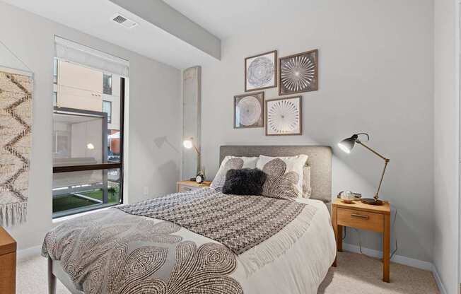 A bedroom with a large bed and a window overlooking a balcony.