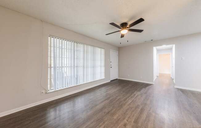 an empty living room with a ceiling fan