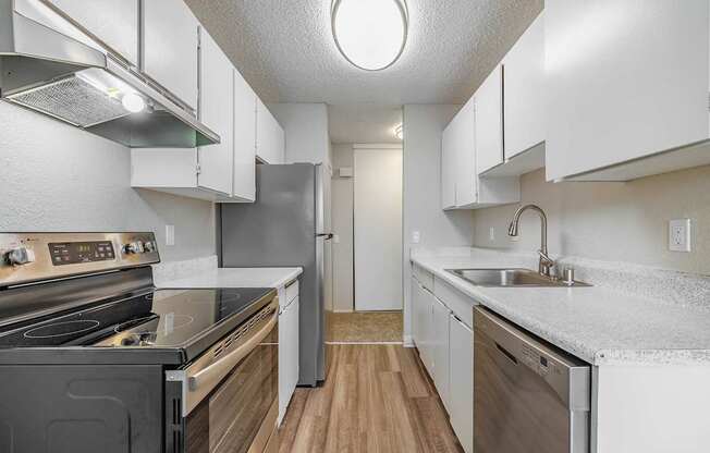 Kitchen with white cabinets, stainless-steel dishwasher, and bright natural light in a Peak 88 apartment in Renton, WA.