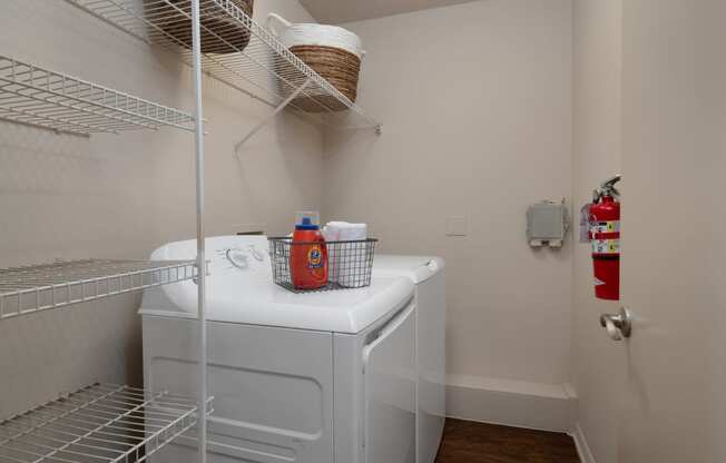 a small laundry room with a washer and dryer and a wire shelf above
