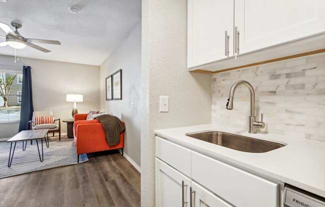 a kitchen with white cabinets and a sink and a living room at Reserve at Temple Terrace, Temple Terrace, FL