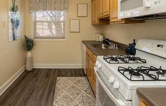 A kitchen with a white gas stove and wooden cabinets at Liberty Gardens Apartments, Baltimore, Maryland